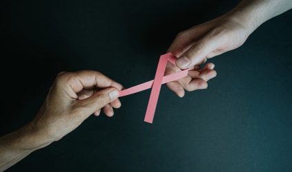 Woman passing pink breast cancer ribbon to another woman